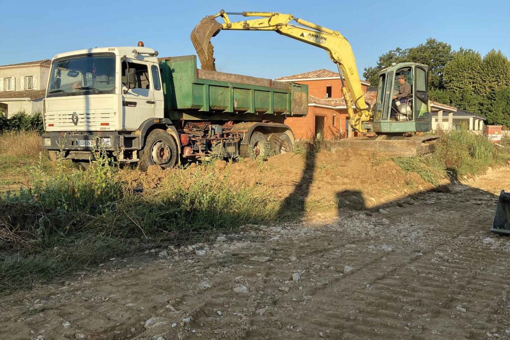 Une pelle chargeant de terre un camion benne - Entreprise de travaux publics